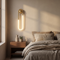Gold wall sconce - Gold Loop LED Wall Sconce beside a bed above a walnut nightstand