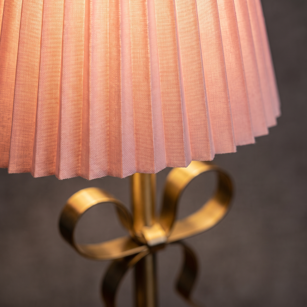 Close-up of the pleated pink shade and brass bow of the Pleated Bow Cordless Table Lamp