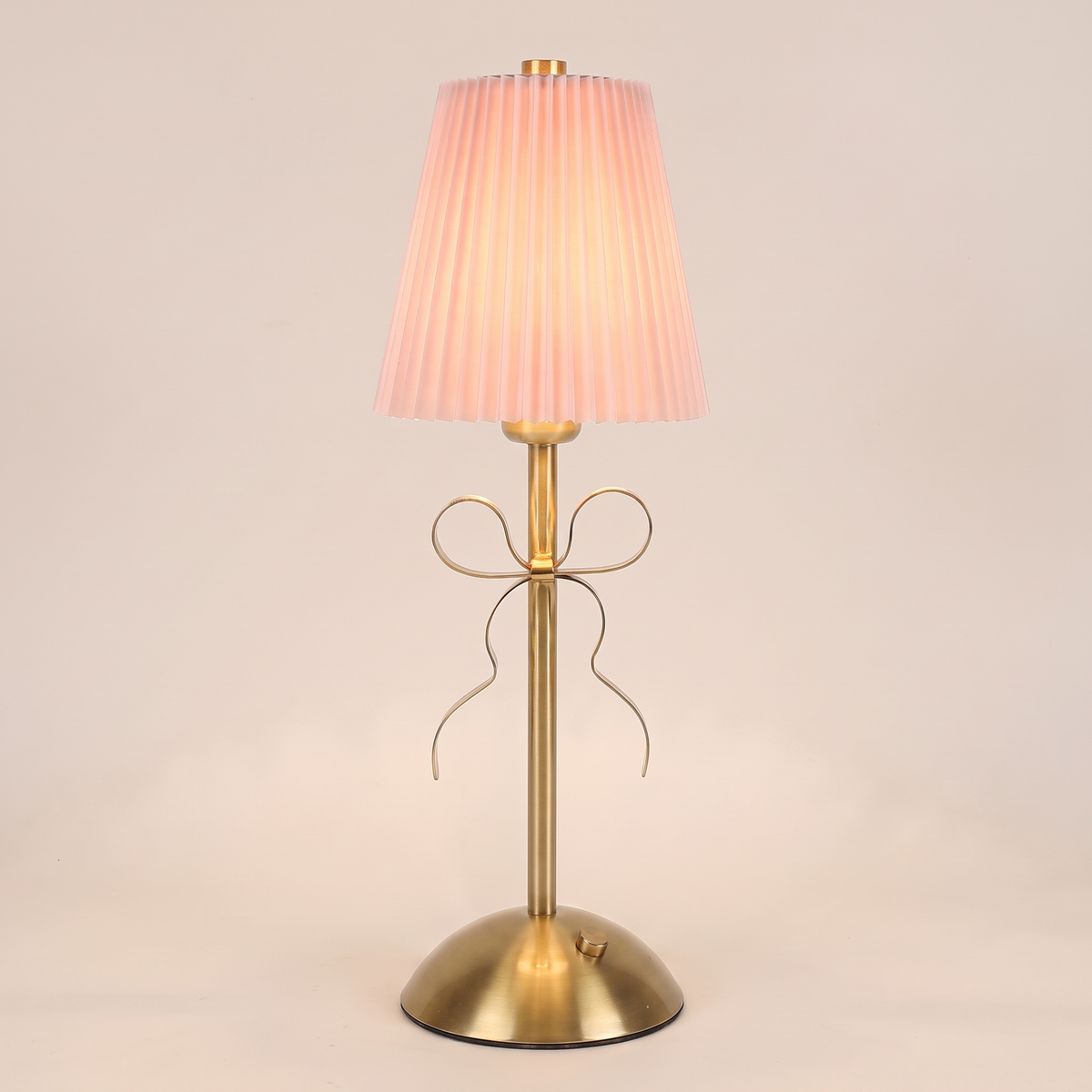 Pleated Bow Cordless Table Lamp in pink, switched on, on a plain background