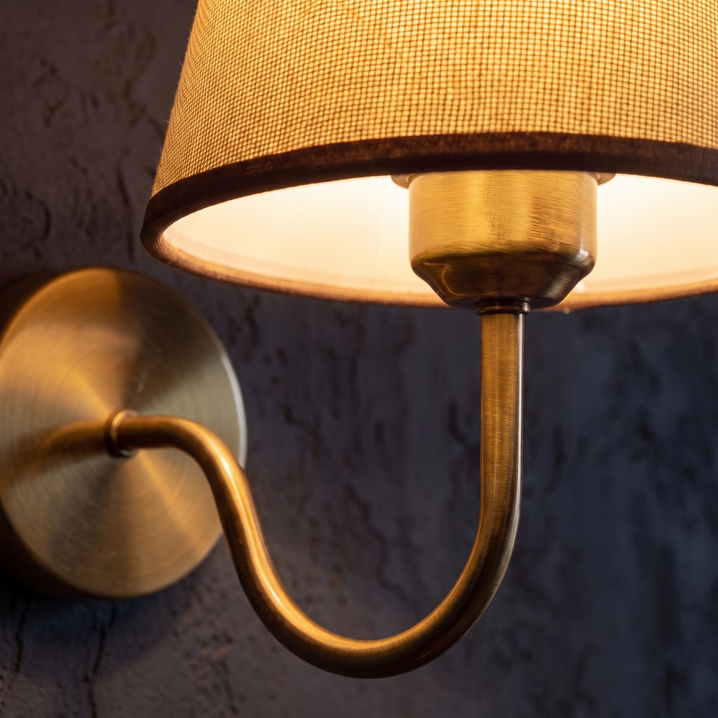 Close-up of the linen shade and brass arm of the rechargeable wall sconce