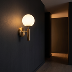 Modern Glass Globe Wall Sconce mounted in a dark hallway washing the wall with warm light