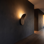 Wave-Form LED Wall Sconce mounted in a dark hallway washing the wall with warm light
