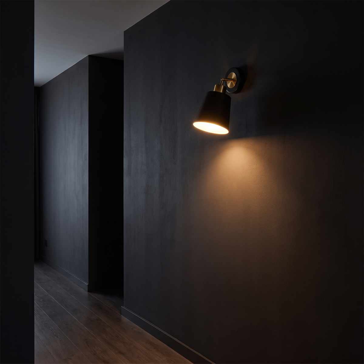 Swivel-Arm Cone Wall Sconce mounted in a dark hallway washing the wall with warm light