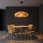 Woven bamboo wave pendant light, hanging over a round oak dining table with rattan chairs