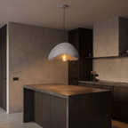 Wabi sabi stone-look pendant light, hanging over a kitchen island with plaster walls