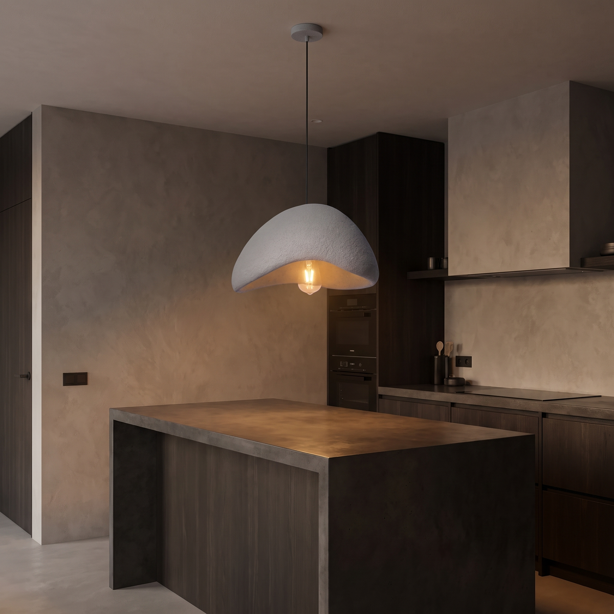Wabi sabi stone-look pendant light, hanging over a kitchen island with plaster walls