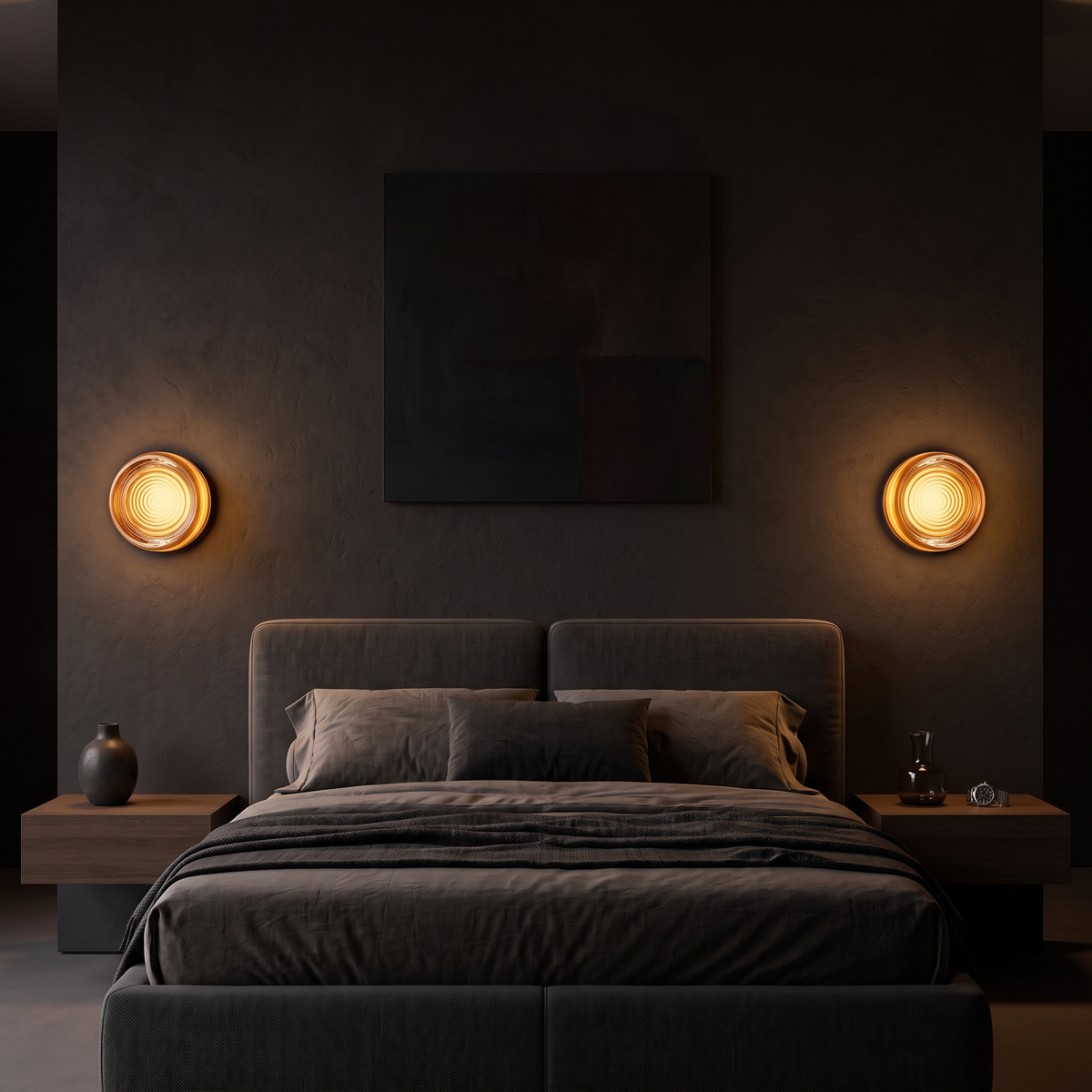 Round amber acrylic LED wall sconces, a pair either side of a bed on a dark plaster wall