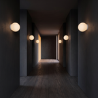 Floating milk glass globe wall sconces along a softly lit hallway