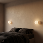 Floating milk glass globe wall sconces, a pair either side of a bed on a warm beige plaster wall