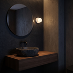 Small white globe wall sconce beside a round mirror in a small bathroom
