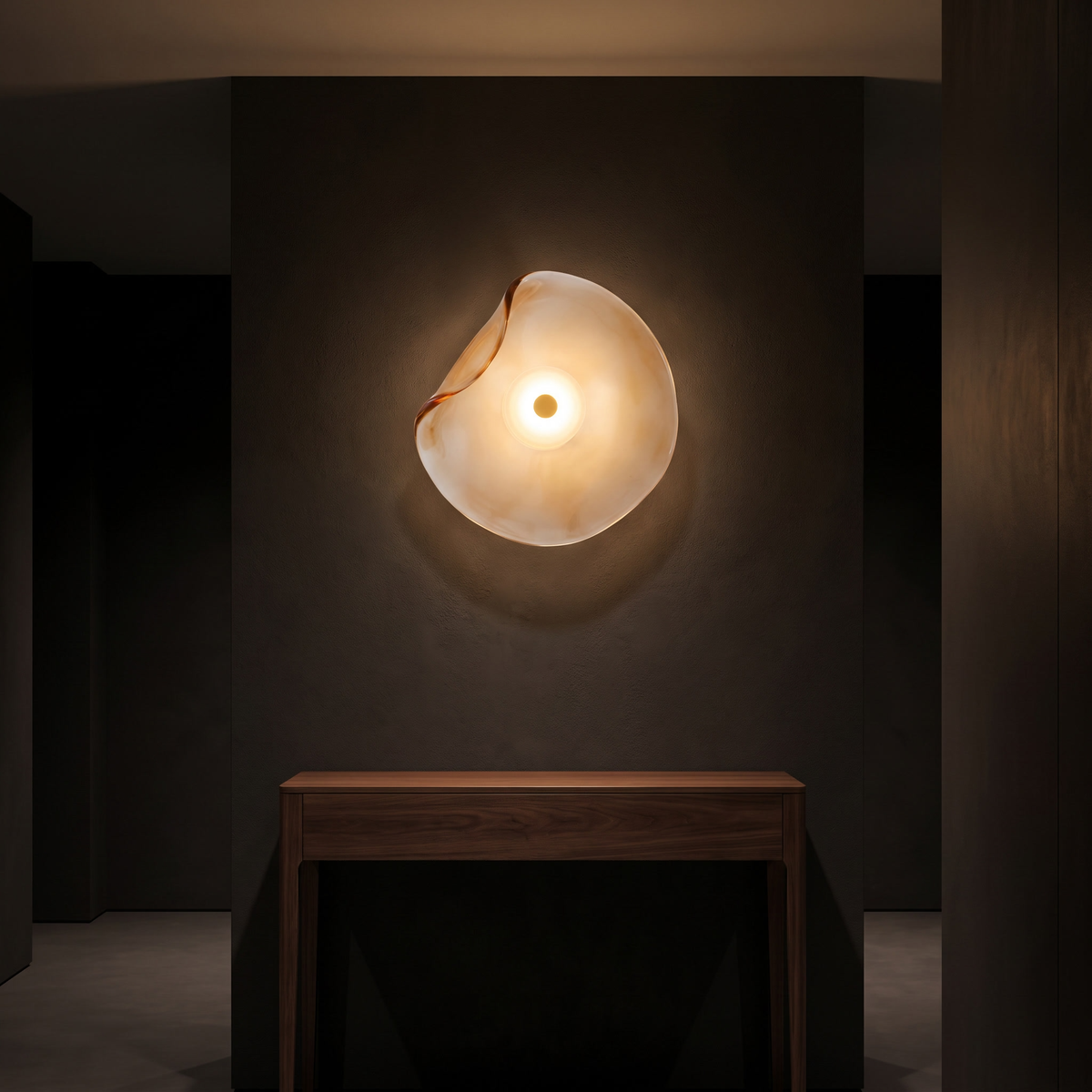 Wavy glass wall sconce above a walnut console in a dark hallway