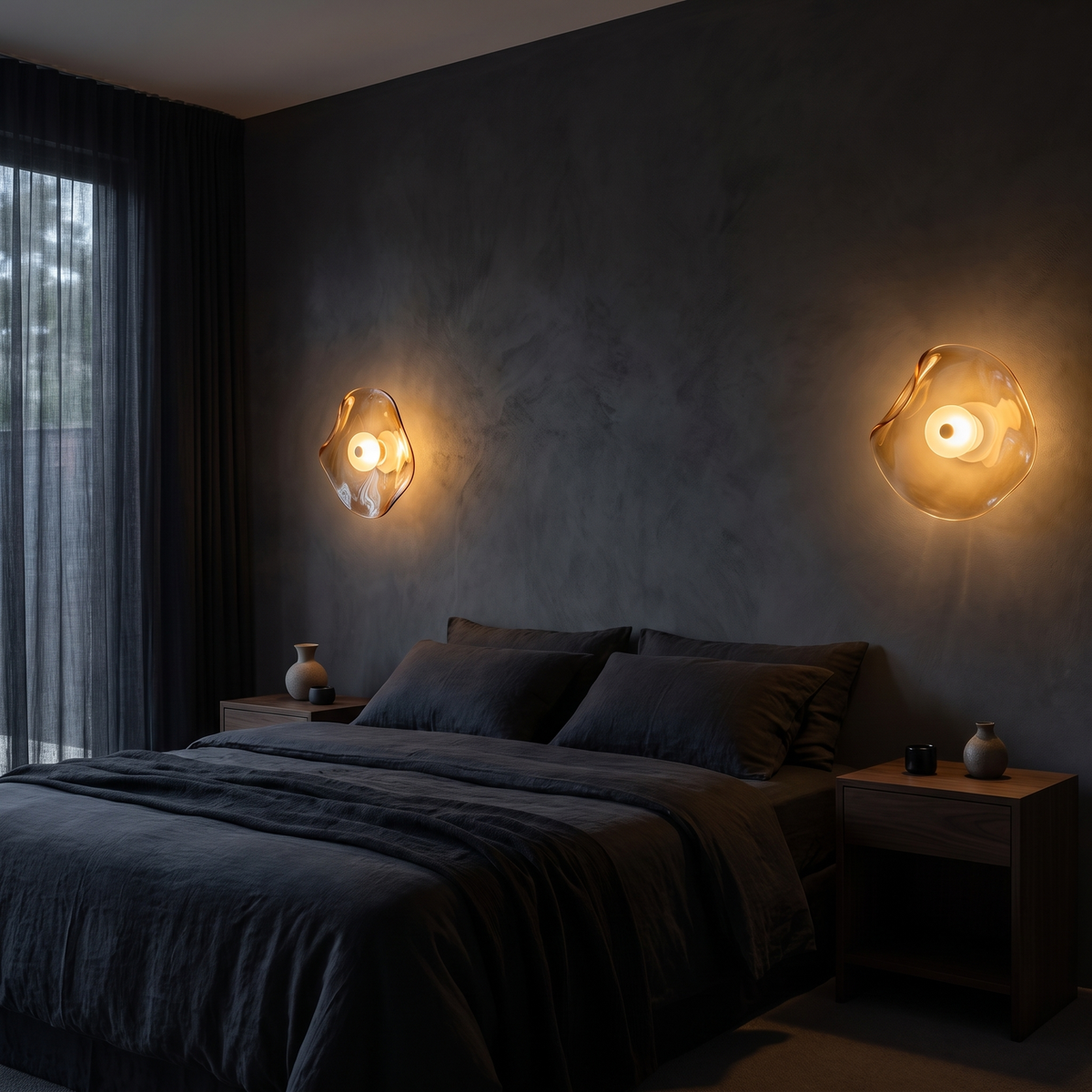 Wavy amber glass wall sconces, a pair on either side of a bed on a dark plaster wall