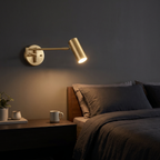 Swing arm cylinder wall sconce shown to scale beside a bed above a nightstand, arm extended