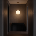 Milk glass globe pendant light shown to scale in a narrow entry hallway above a console table