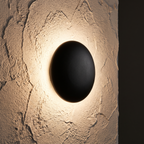 Black Pebble Wall Light close-up on a textured plaster wall