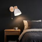 Nordic Wood Wall Sconce with Pull Chain in white beside a bed