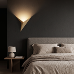 Gold Triangle LED Wall Sconce beside a bed at night