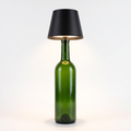 Black round shade cordless bottle lamp on a green bottle, white background