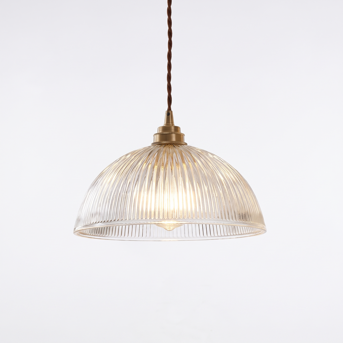 Ribbed glass dome pendant light with brass socket on white background