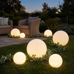 Glowing LED ball lights on a garden lawn at dusk