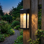 Solar wall lantern on a garden fence post at twilight