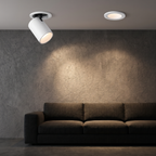 White adjustable recessed spotlights washing a living room wall above a sofa