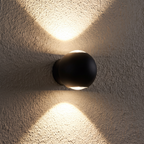 Close-up of the Modern Sphere Up Down Wall Light casting up and down beams on a textured wall