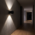 Modern Sphere Up Down Wall Light in a dark grey hallway at night