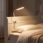Modern Clip On Desk Lamp clamped to a white bed headboard at night