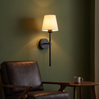 Modern Cordless Wall Sconce above a leather armchair on an olive green wall