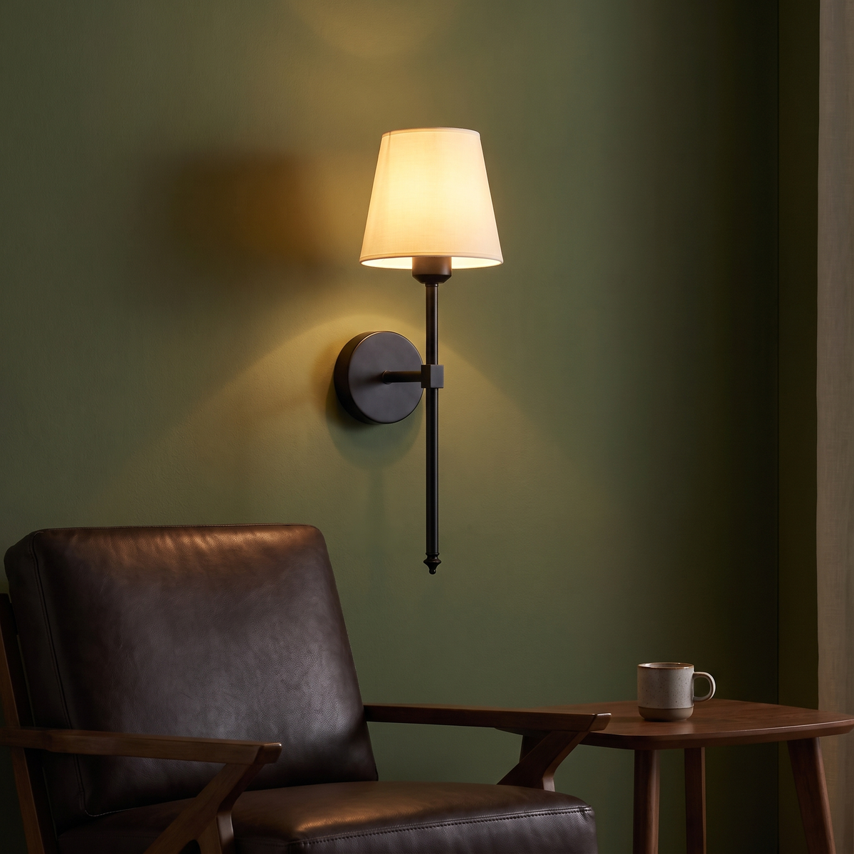 Modern Cordless Wall Sconce above a leather armchair on an olive green wall