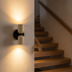 Modern Black and Ivory Up Down Sconce beside an oak staircase