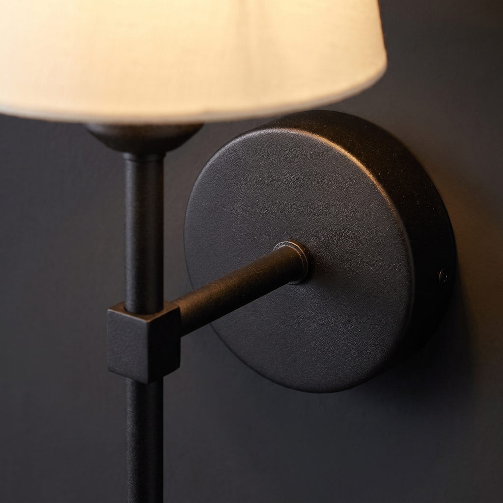 Close-up of the round matte black wall plate, arm and collar on the cordless wall sconce