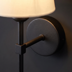 Close-up of the round matte black wall plate, arm and collar on the cordless wall sconce