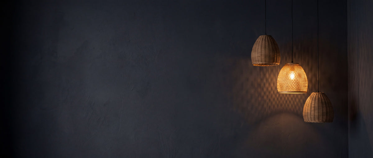Three rattan pendant lights against a charcoal wall